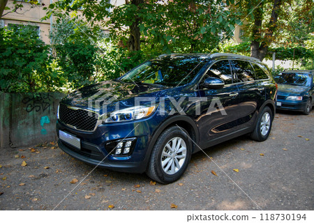 Beautiful car close-up. A dark KIA crossover stands in the driveway of the courtyard. 118730194