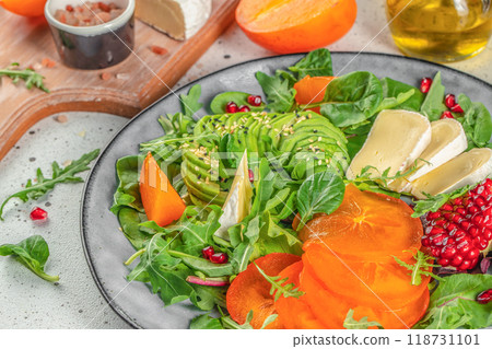 vitamin winter salad with persimmons, fresh greens, avocado, Camembert cheese and pomegranate. organic healthy products. top view 118731101