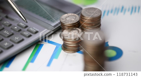 Silver calculator with keyboard lying on desk cash quarter plots in home office setting 118731143
