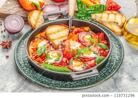 Shakshuka fried eggs, tomatoes, onion, pepper in iron pan, traditional Arabic dish, place for text, top view Shakshuka fried eggs, tomatoes, onion, pepper in iron pan, traditional Arabic dish, place for text, top view 118731296