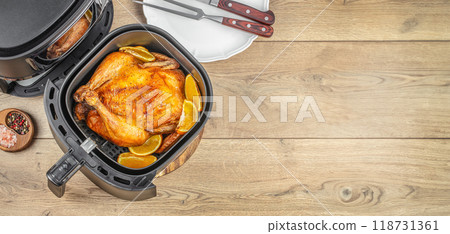 Roasted chicken from the hot air fryer oven on wooden table. Homemade Thanksgiving dish. top view. copy space Roasted chicken from the hot air fryer oven on wooden table. Homemade Thanksgiving dish. top view. copy space 118731361
