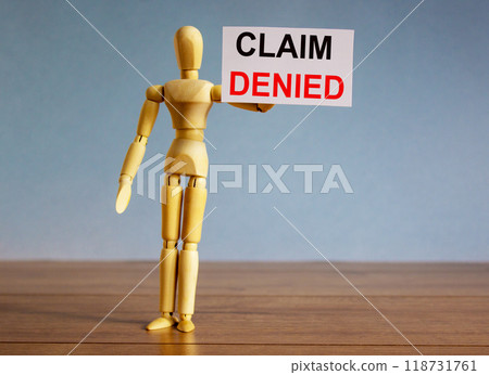 Wooden model of a man holding a tablet saying claim denied. Wooden model of a man holding a tablet saying claim denied. 118731761