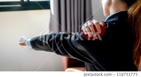 A successful businesswoman feeling shoulder pain and stretching herself after working hard on computer laptop for a long time on sofa in the home office, Office syndrome concept 118731775
