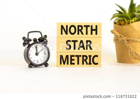 North star metric symbol. Concept words North star metric on wooden blocks on a beautiful white table white background. Black alarm clock. Business, finacial and north star metric concept. Copy space. 118731822