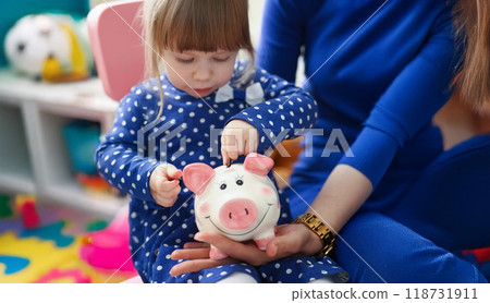 Cute little child putting coin cash into piggy bank container Cute little child putting coin cash into piggy bank container 118731911