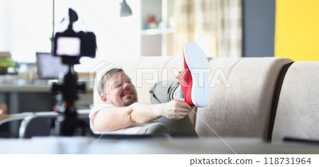 Middle aged male putting on trendy red sneaker showing on camera 118731964