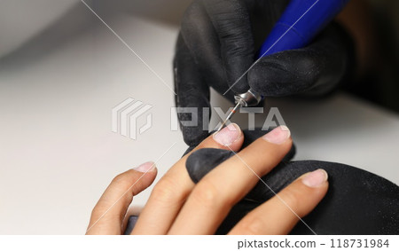 Nail master using tool to clean female clients nails in beauty studio 118731984