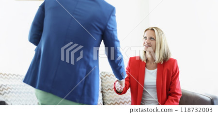 Attractive young female greeting man with handshake sitting on couch Attractive young female greeting man with handshake sitting on couch 118732003