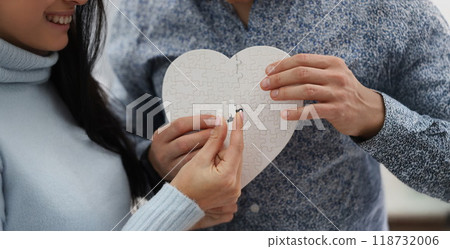 Woman and man fill empty space with missing piece of white heart puzzle 118732006