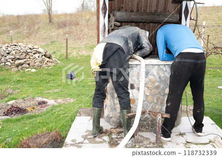 Two men lower the hose into the well. Two men lower the hose into the well. 118732339
