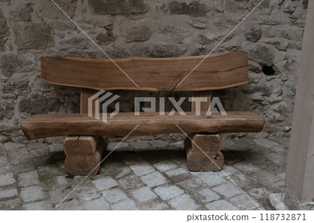 wooden bench by the stone pavement. Wooden benches from a tree trunk. Rest area near the castle. wooden bench by the stone pavement. Wooden benches from a tree trunk. Rest area near the castle. 118732871
