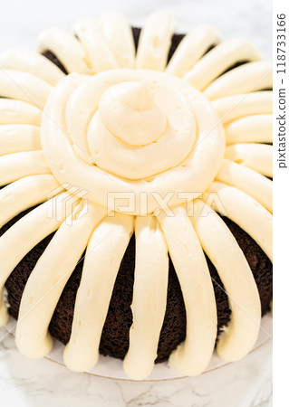 With precision, the Chocolate Bundt Cake is carefully removed from the pan - adorned with luscious cream cheese frosting, creating a delectable treat that is sure to delight. With precision, the Chocolate Bundt Cake is carefully removed from the pan - adorned with luscious cream cheese frosting, creating a delectable treat that is sure to delight. 118733166