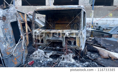Burnt-out trucks against the background of a broken building. Panorama. Burnt-out trucks against the background of a broken building. Panorama. 118733385