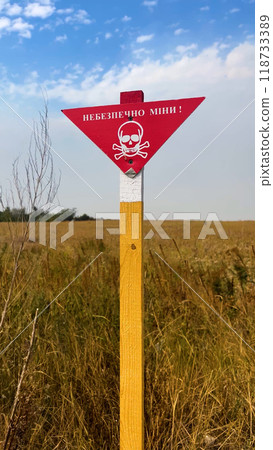 A red warning sign with the inscription Mine Danger and an image of a skull with crossbones. A red warning sign with the inscription Mine Danger and an image of a skull with crossbones. 118733389