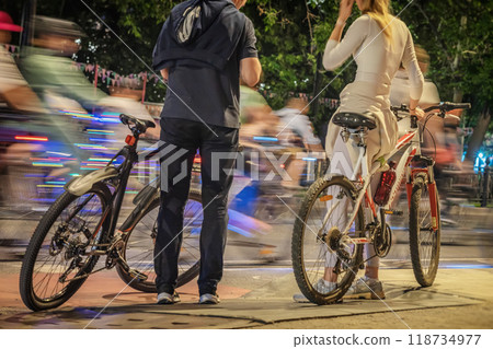Couple enjoying a vibrant evening bike ride in lively urban environment, abstract blurred background 118734977