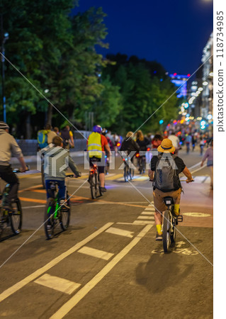 Cyclists riding through a vibrant city street at night during community biking event in summer 118734985