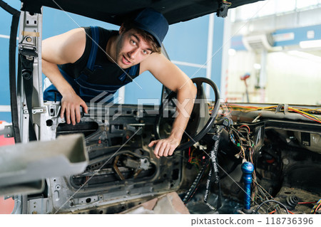 Portrait from interior of old vehicle to skilled mechanic in overalls inspecting inside car after removing dashboard, showing expertise in troubleshooting automotive problems. Concept of car repair Portrait from interior of old vehicle to skilled mechanic in overalls inspecting inside car after removing dashboard, showing expertise in troubleshooting automotive problems. Concept of car repair 118736396