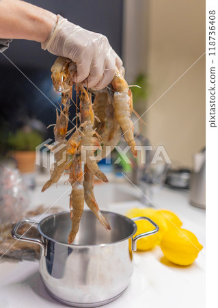 Cropped hand holding shrimps in kitchen 118736408