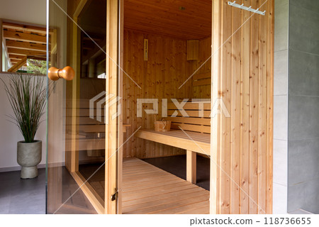 Wooden Sauna With Benches. The sauna is empty. The wooden benches provide seating for people. 118736655