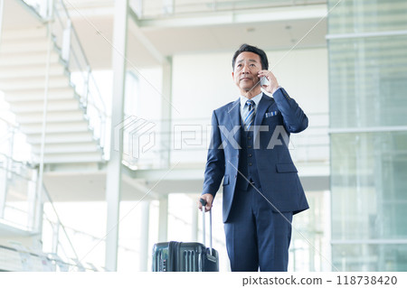 Middle-aged businessman making a phone call at the airport Middle-aged businessman making a phone call at the airport 118738420