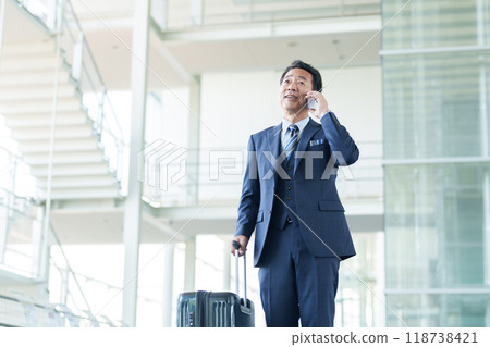 Middle-aged businessman making a phone call at the airport 118738421
