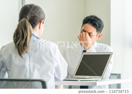 一名男商人在健康檢查期間接受女醫生的訪談（身體檢查、眼睛疲勞、過度勞累、身體檢查） 118738715