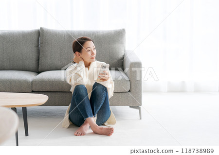 A woman sitting on the floor in the living room and using her smartphone 118738989