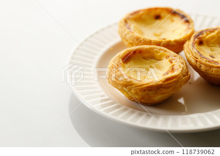 Stack of Portuguese sweet dessert egg tart or Pastel de Nata on white ceramic plate on white table. Copy space. Selective focus. 118739062
