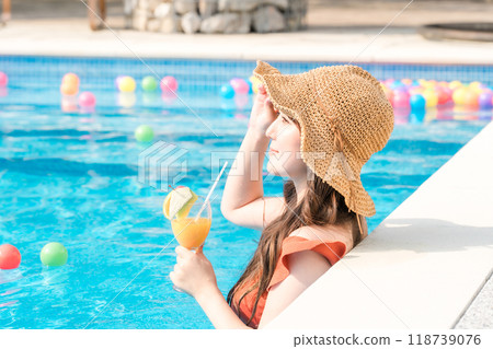Young Asian woman drinking a tropical drink in the pool on a resort vacation. Pool, Summer, Leisure, Young Asian woman drinking a tropical drink in the pool on a resort vacation. Pool, Summer, Leisure, 118739076