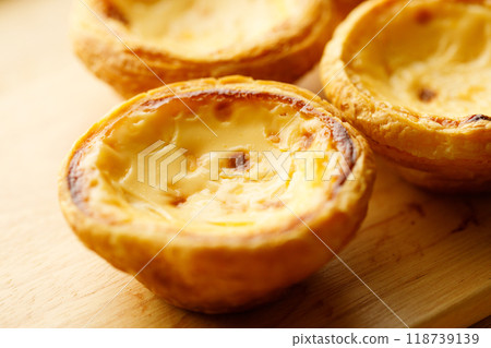 Stack of Portuguese sweet dessert egg tart or Pastel de Nata on wooden board on wooden table.  Selective focus. 118739139