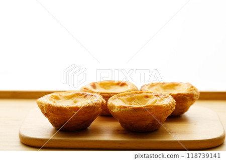 Stack of Portuguese sweet dessert egg tart or Pastel de Nata on wooden board on wooden table.  Selective focus. Stack of Portuguese sweet dessert egg tart or Pastel de Nata on wooden board on wooden table.  Selective focus. 118739141