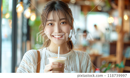 Young woman drinking iced cafe au lait in a bright cafe 118739997