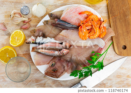 Variety of fresh raw fish and shrimp on plate with lemon and greens Variety of fresh raw fish and shrimp on plate with lemon and greens 118740174