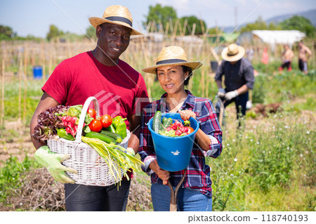 Man and woman posing with basket of vegetables on the field Man and woman posing with basket of vegetables on the field 118740193