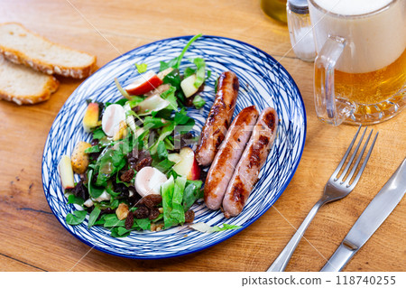 Grilled sausages with salad, walnuts and raisins closeup 118740255