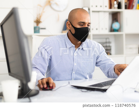Coronavirus.Man with face mask working at computer during coronavirus epidemic. Prevention of COVID-19 infection 118740576