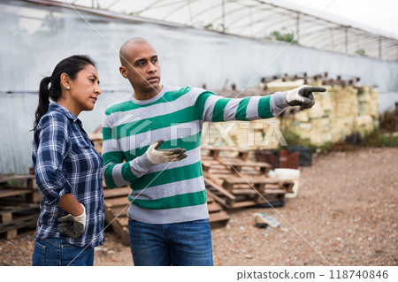 Latino man and woman talking near greenhouse Latino man and woman talking near greenhouse 118740846