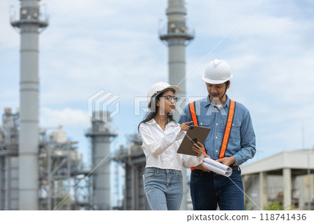 Engineer with blueprint and tablet working factory producing electricity oil energy. 118741436