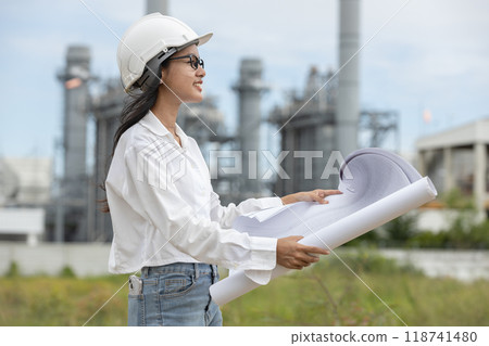 Engineer with blueprint working factory producing electricity oil energy. Engineer with blueprint working factory producing electricity oil energy. 118741480
