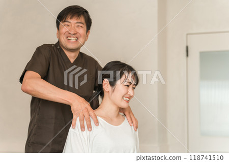 A woman who goes to a chiropractic clinic, osteopathic clinic, and massage clinic for treatment of stiff shoulders, and a chiropractor/therapist A woman who goes to a chiropractic clinic, osteopathic clinic, and massage clinic for treatment of stiff shoulders, and a chiropractor/therapist 118741510