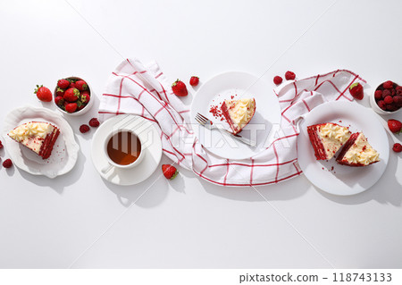 Pieces of red velvet cake on plates, berries and towel on white background, top view Pieces of red velvet cake on plates, berries and towel on white background, top view 118743133