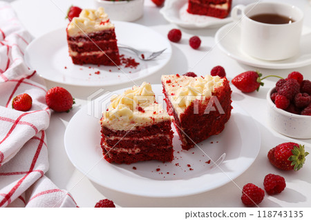 Pieces of red velvet cake on plates, berries and towel on white background 118743135