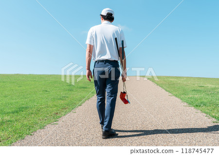 一名男子帶著推桿和高爾夫球桿在高爾夫球場行走的後視圖 118745477