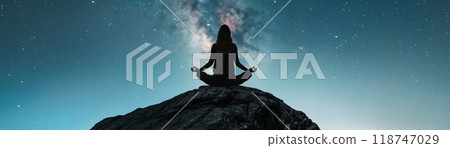 Silhouette of a person meditating on a rock under a starry sky, achieving inner peace and tranquility in nature. 118747029