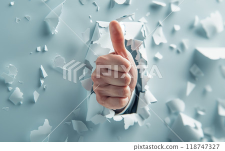 Thumbs up hand gesture breaking through a wall, symbolizing success, approval, and achievement in a creative and dynamic visual. 118747327