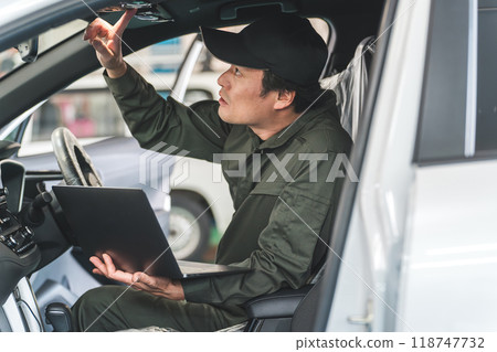 一位男性汽車修理工在車上使用筆記型電腦 一位男性汽車修理工在車上使用筆記型電腦 118747732