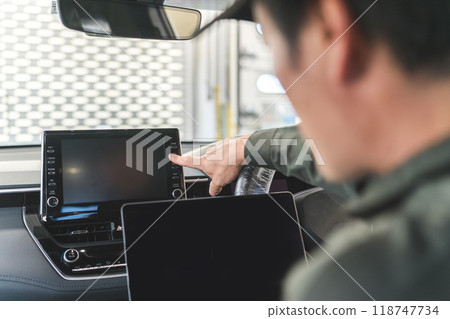 一位男性汽車修理工在車上使用筆記型電腦 一位男性汽車修理工在車上使用筆記型電腦 118747734