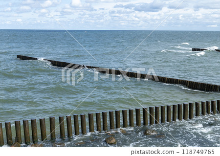 Coastal view with shore water and wooden breakwater structures Coastal view with shore water and wooden breakwater structures 118749765