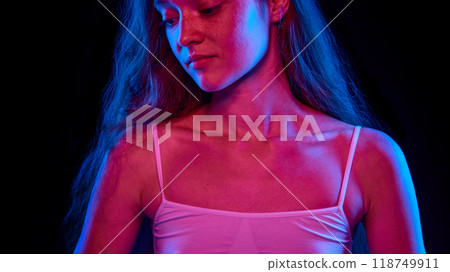 Cropped image of female body, collarbone. Model posing in top, showing her healthy and slim body against black background in neon light 118749911