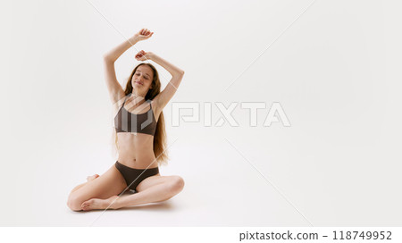 Young beautiful woman taking care of herself, sitting on floor in underwear, posing isolated on white studio background. Relaxation and calmness 118749952